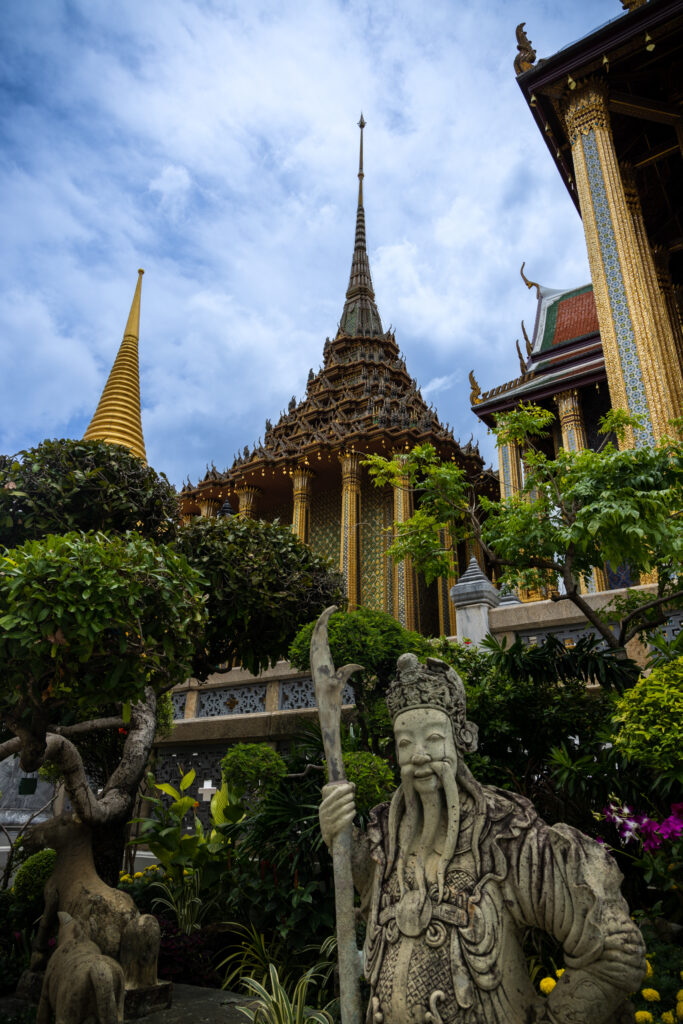 statue surrounded by green trees in the grand palace in Bangkok