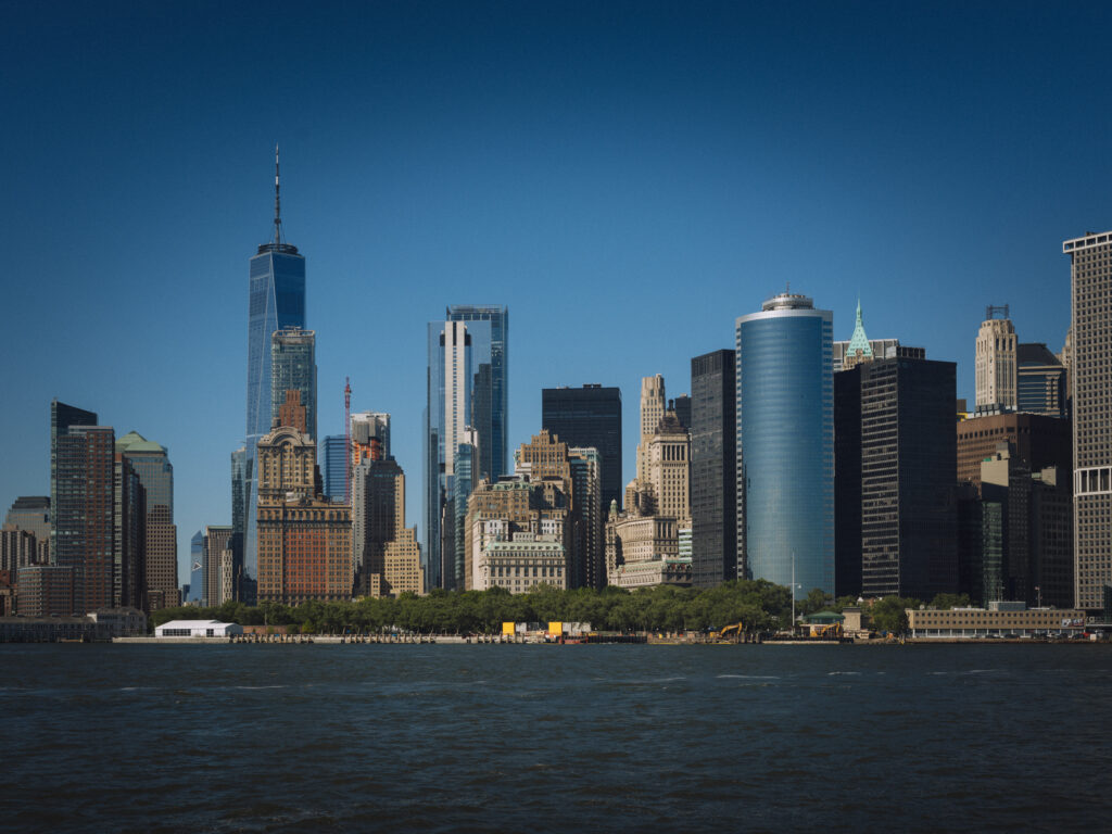 Lower Manhattan's skyline, anchored by One World Trade Center, rises above the Hudson River on a clear day, New York City